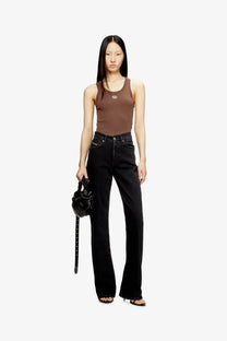 Black patent leather mini bag with long strap and structured rounded shape paired with diesel brown ribbed tank top
