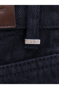 Silver rectangular metal tag with cd engraved attached to dark blue denim on back side of dior men’s cotton jeans