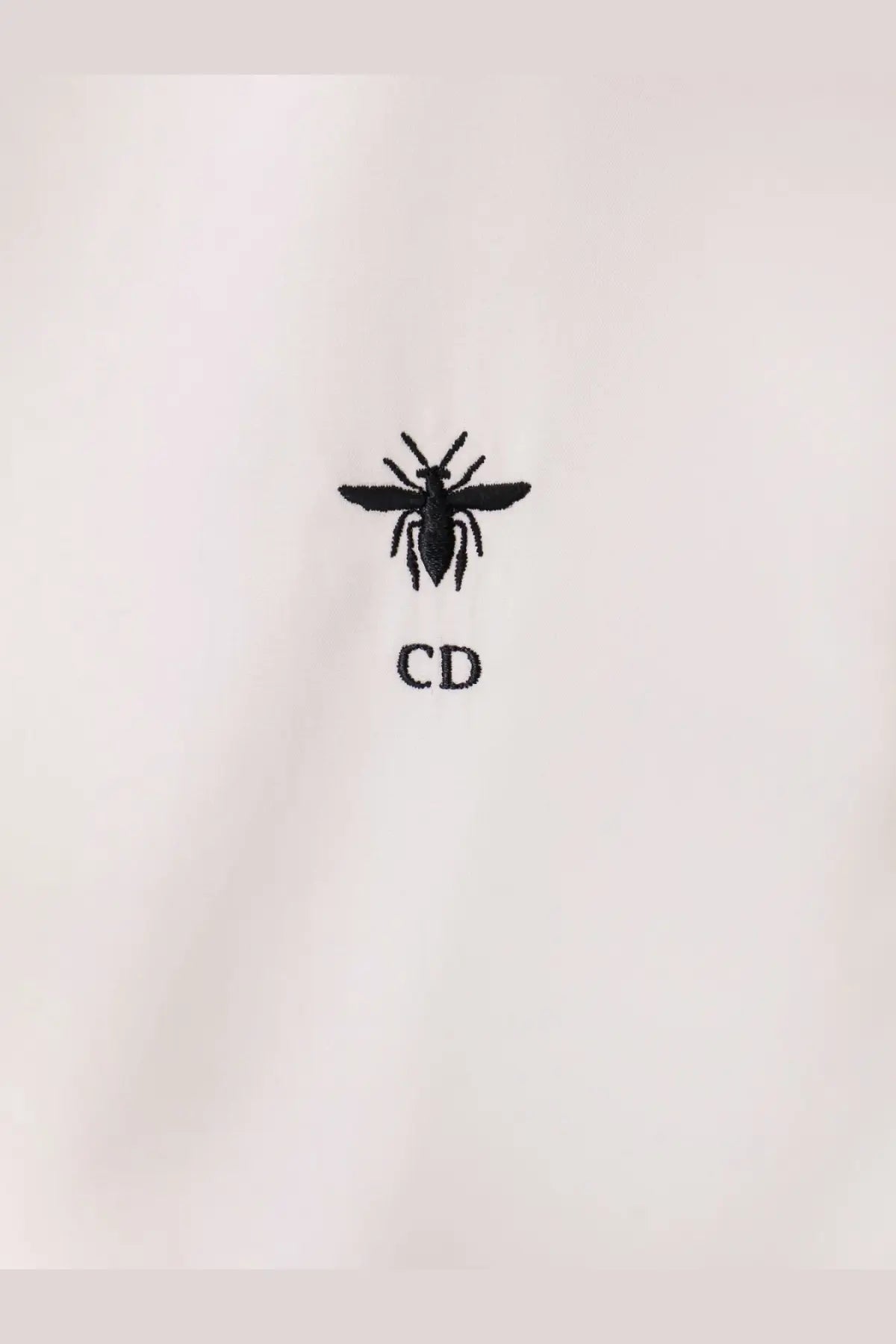 Black embroidered bee logo with cd initials on white cotton fabric of dior womens cotton shirt front side