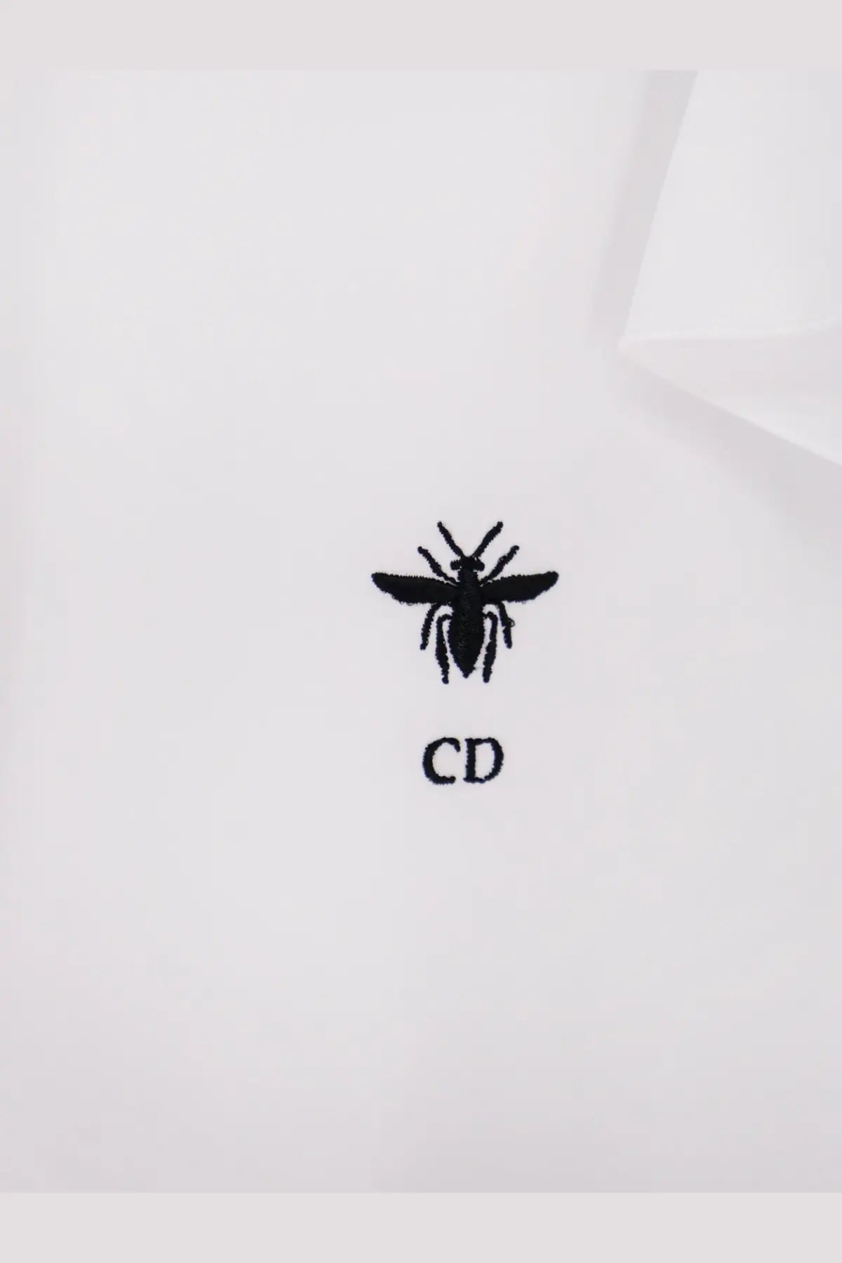 Black embroidered bee logo with cd initials on white cotton fabric of dior womens cotton shirt front side