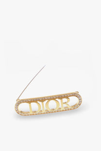 Gold-tone Dior women’s brass brooch with Dior lettering outlined in pave-set stones for elegant accessorizing