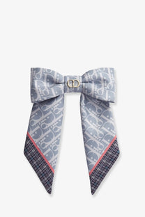 Gray dior bow tie scarf with repeating monogram pattern and plaid trim styled with dior twist infini tartan print silk hair clip blue