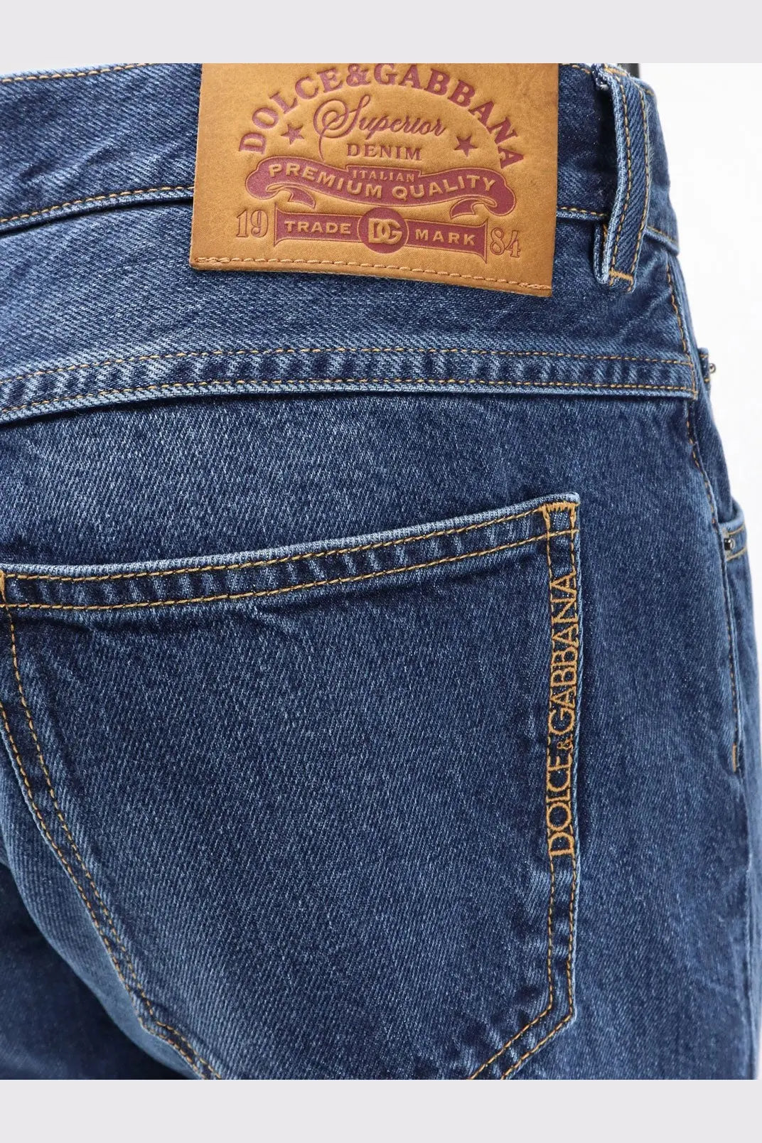 Back view of dolce &amp; gabbana men’s blue denim jeans with brown leather patch and gold thread stitching on pocket seam