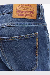 Back view of dolce &amp; gabbana men’s blue denim jeans with brown leather patch and gold thread stitching on pocket seam