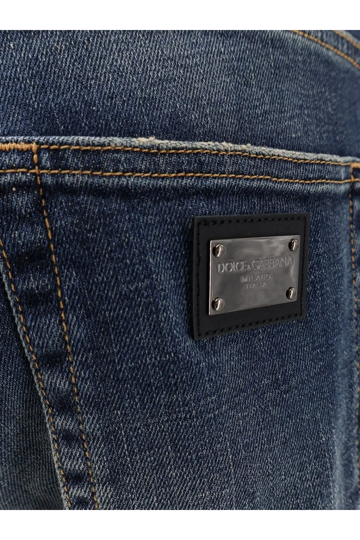 Dark blue denim jeans with black leather patch and silver dolce and gabbana logo plaque on the back side