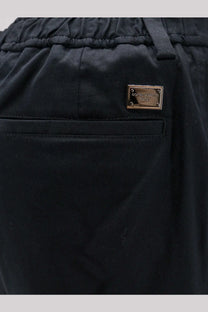 Back side of black cotton Dolce &amp; Gabbana men’s cargo trousers with metallic gold-tone brand plaque on the pocket