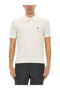 Cream-colored knit polo shirt with ribbed hem and collar featuring a small rectangular logo patch on left chest by Dolce &amp; Gabbana
