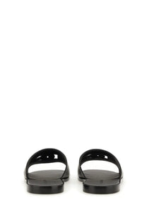 Black glossy rubber slide sandals with minimalist cut-out design for men by Dolce &amp; Gabbana