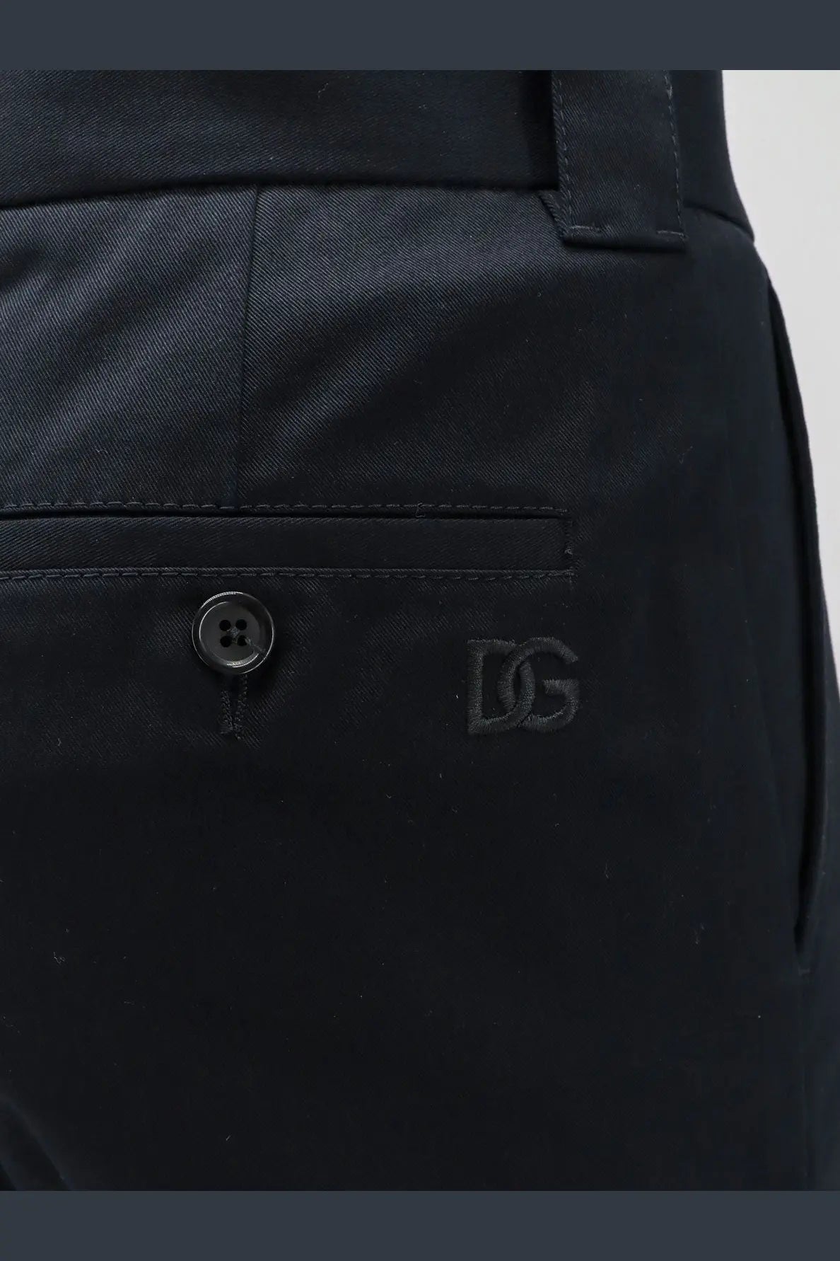 Black dg logo embroidered on the front pocket of dark navy cotton chino pants from dolce and gabbana men’s trousers