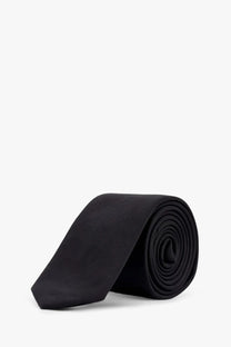 A sleek black silk tie by dolce and gabbana neatly rolled displayed against a clean white background