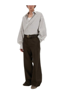 A black leather belt with a gold-tone Dolce &amp; Gabbana dg logo buckle shown with men’s tailored brown pants