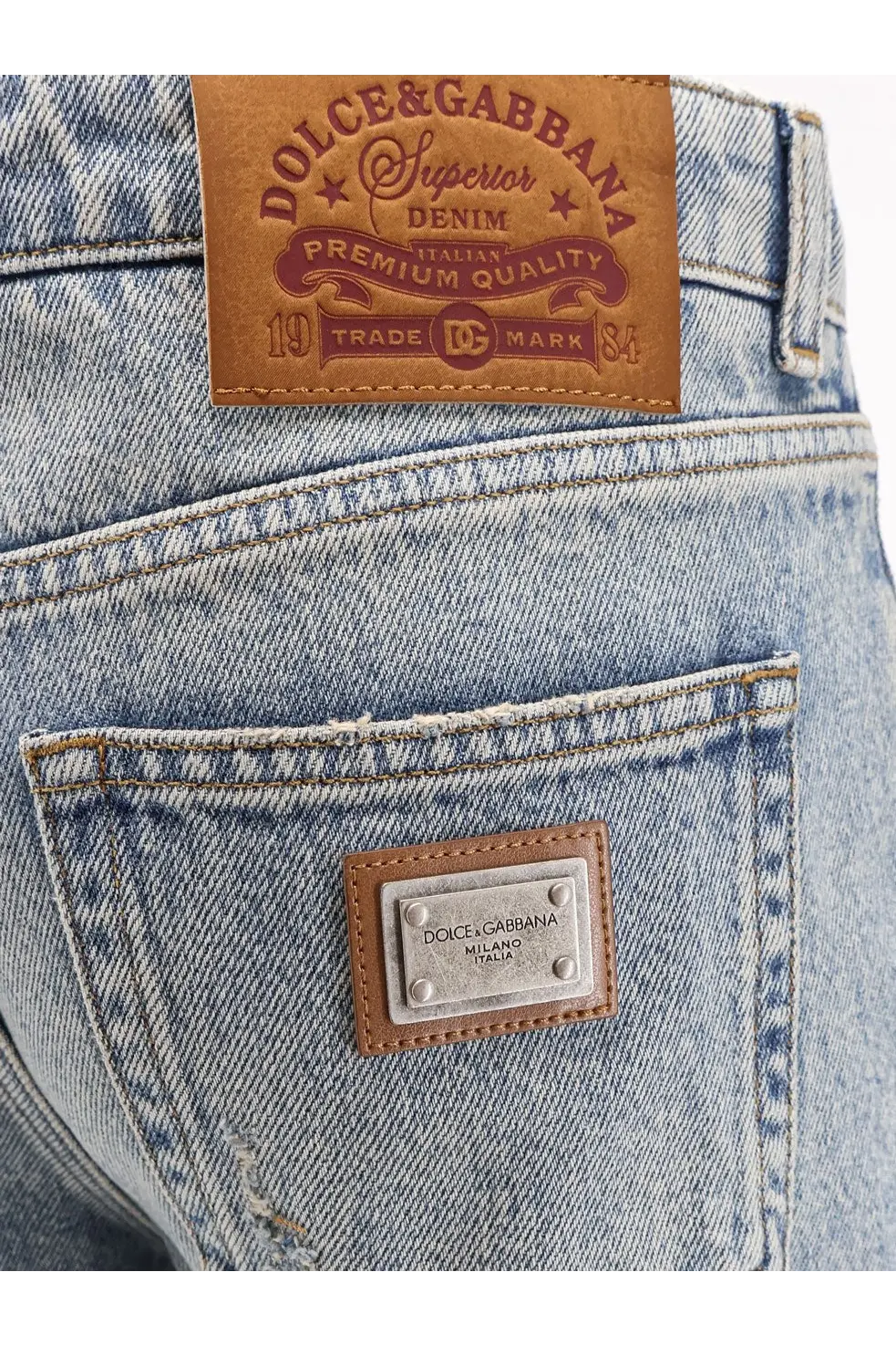 Back side of dolce and gabbana women’s blue light-wash denim jeans with brown leather patch and metallic plaque