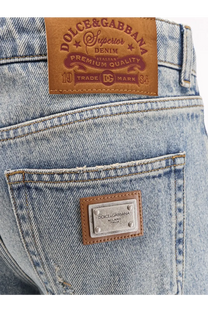 Back side of dolce and gabbana women’s blue light-wash denim jeans with brown leather patch and metallic plaque