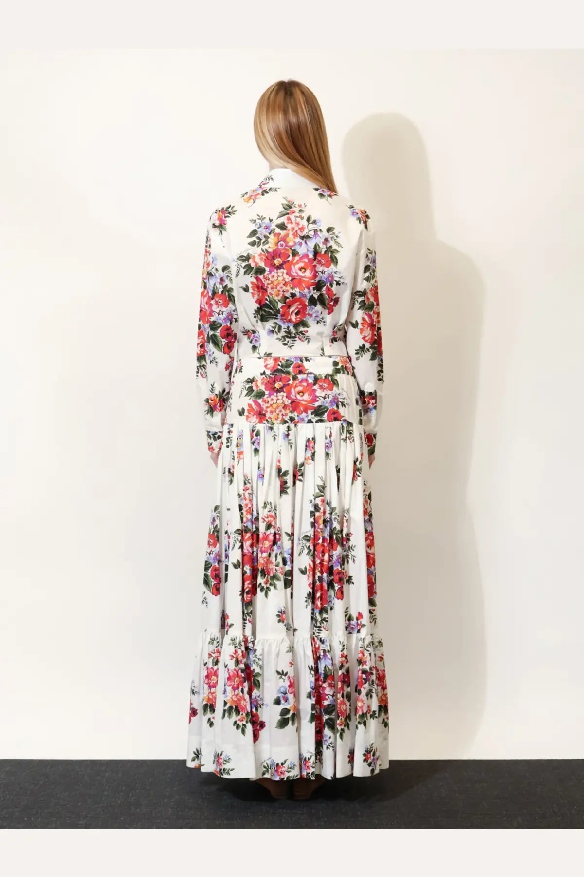 A woman wears a Dolce &amp; Gabbana white cotton shirt with a long white maxi dress featuring red and purple floral patterns