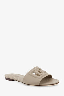 Beige leather slide sandal by Dolce &amp; Gabbana featuring a prominent embossed interlocking cc logo on the strap