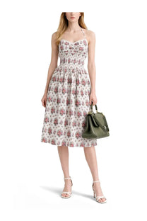 A woman wearing a multicolor floral print Dolce &amp; Gabbana midi dress with thin straps and white heeled sandals
