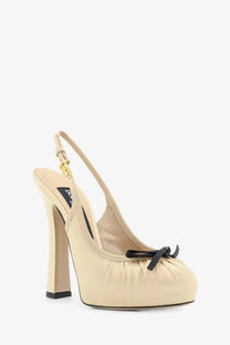 Dolce &amp; Gabbana women’s beige satin slingback pump with black bow and gold-tone hardware at the toe