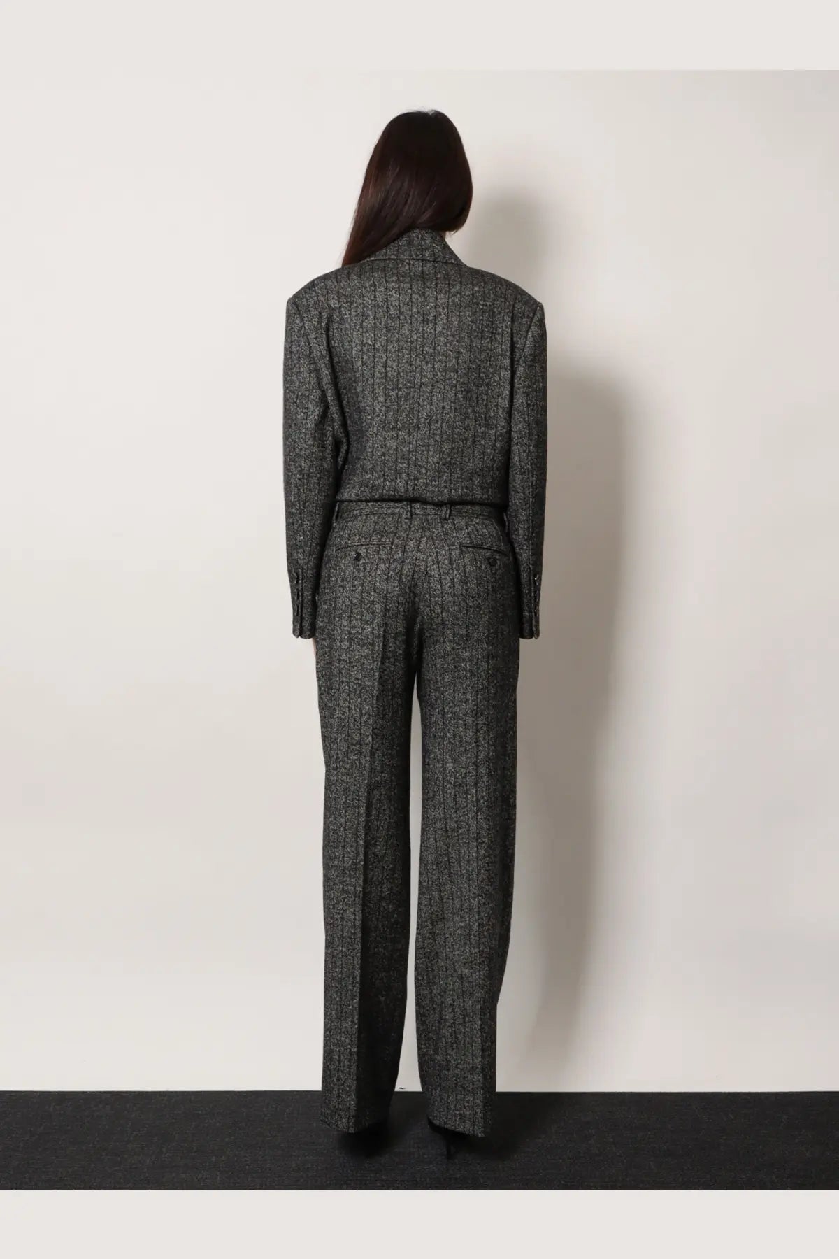 A tailored charcoal gray herringbone wool suit with high collar and matching belt paired with dolce and gabbana striped wool blend trousers