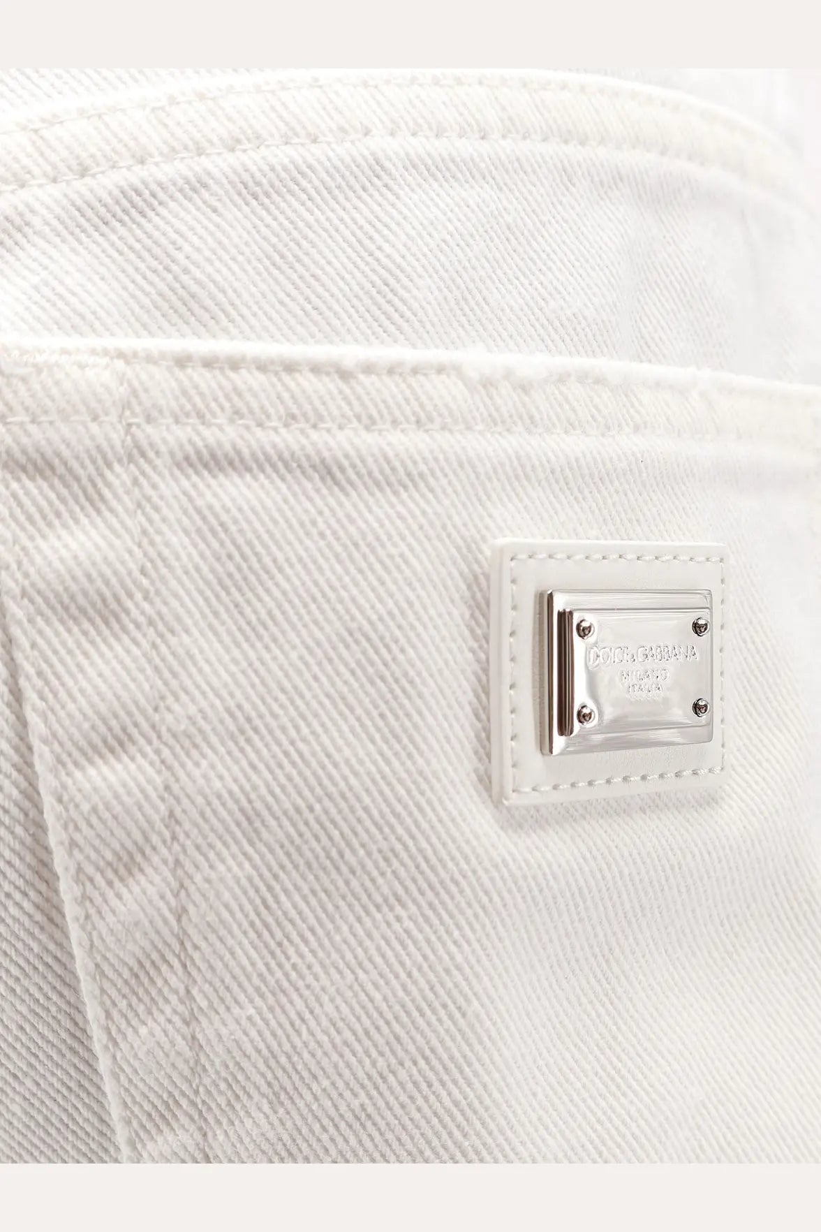 Dolce &amp; Gabbana women’s white denim shorts featuring a silver-tone metal plaque with the brand logo on the back
