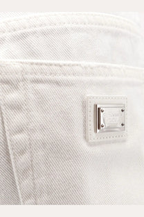 Dolce &amp; Gabbana women’s white denim shorts featuring a silver-tone metal plaque with the brand logo on the back