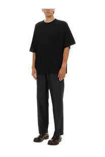 Black oversized short-sleeved t-shirt with relaxed fit and subtle hemline paired with dries van noten men’s penny grey pants