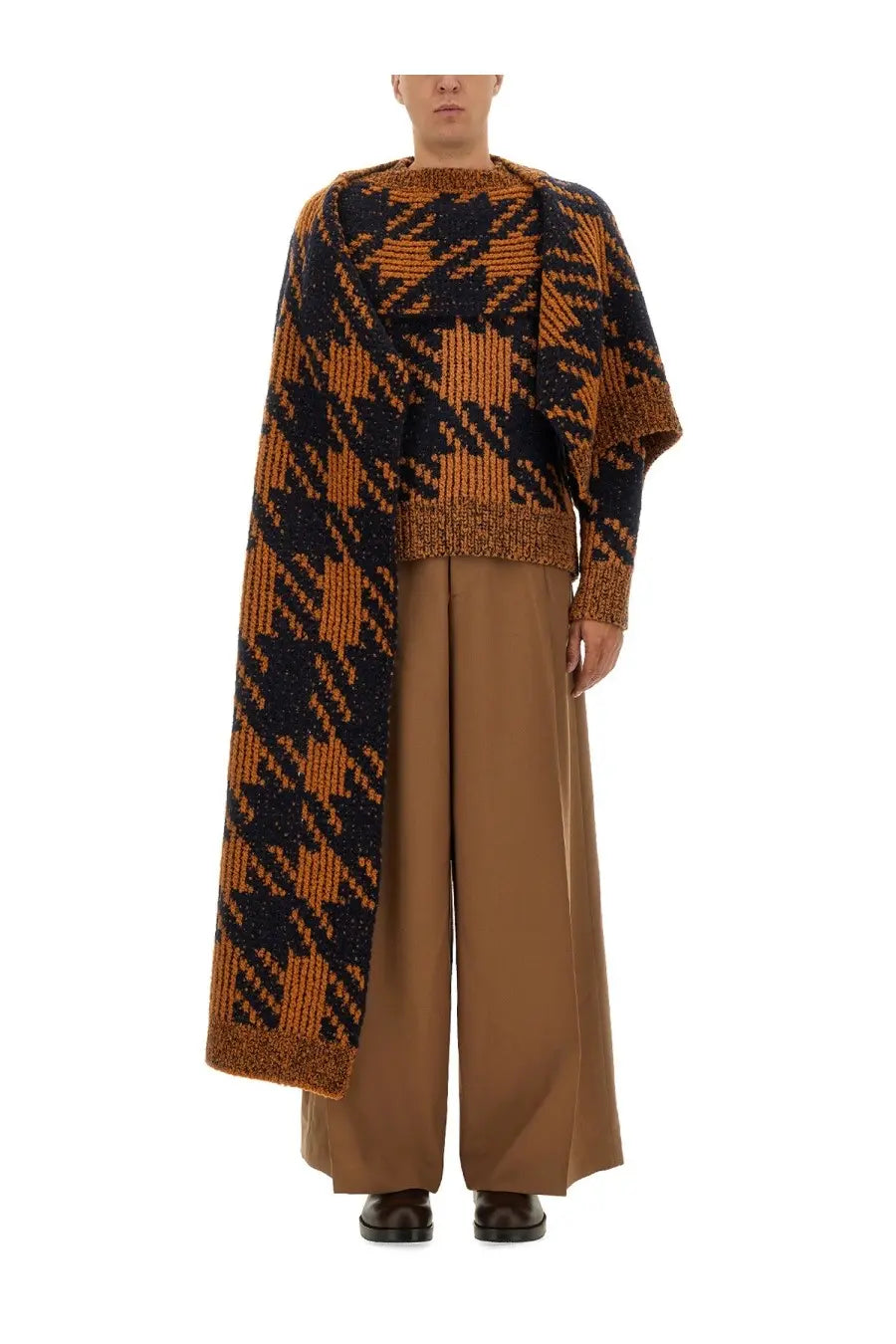 Knitted asymmetrical poncho with bold black and rust houndstooth pattern made of textured wool yarn by dries van noten