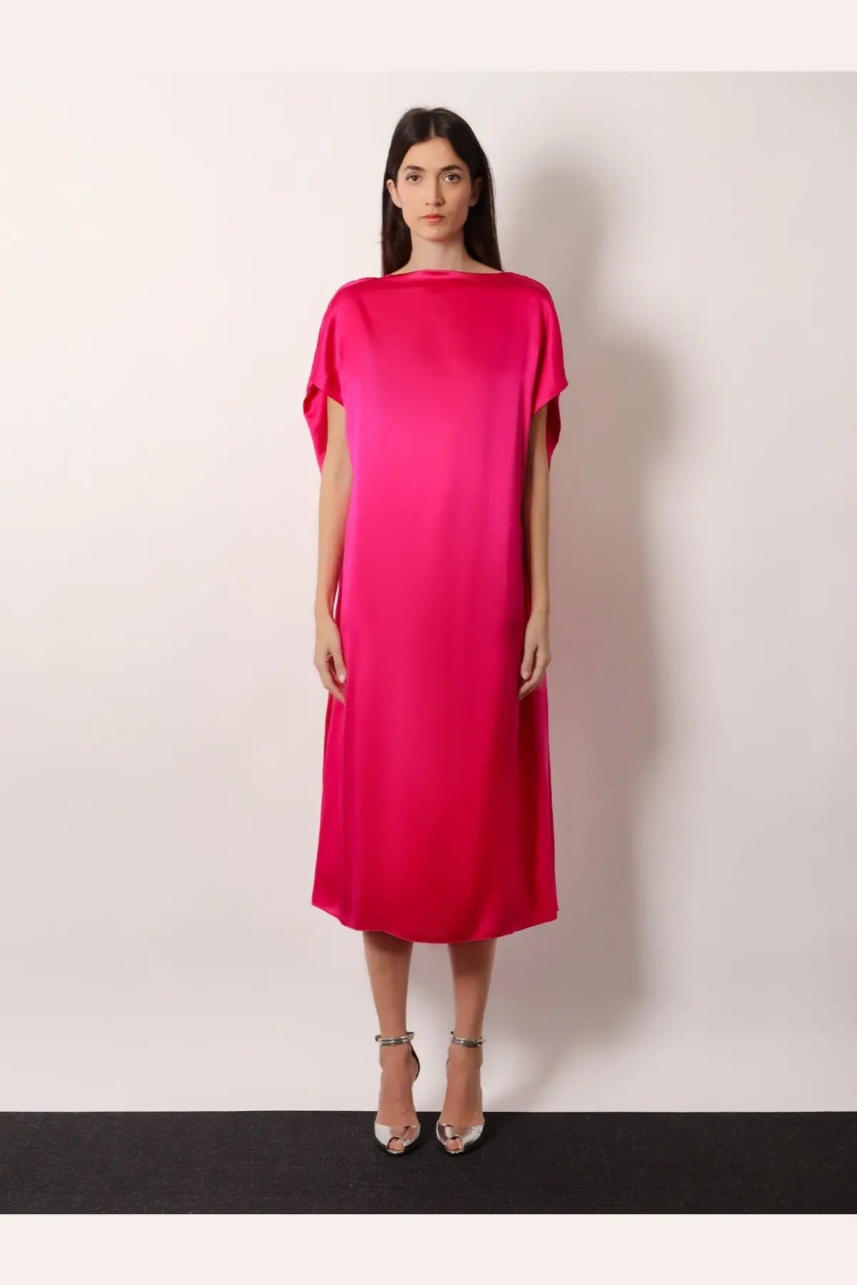 A vibrant fuchsia satin midi dress with a loose flowing silhouette and cape sleeves by dries van noten