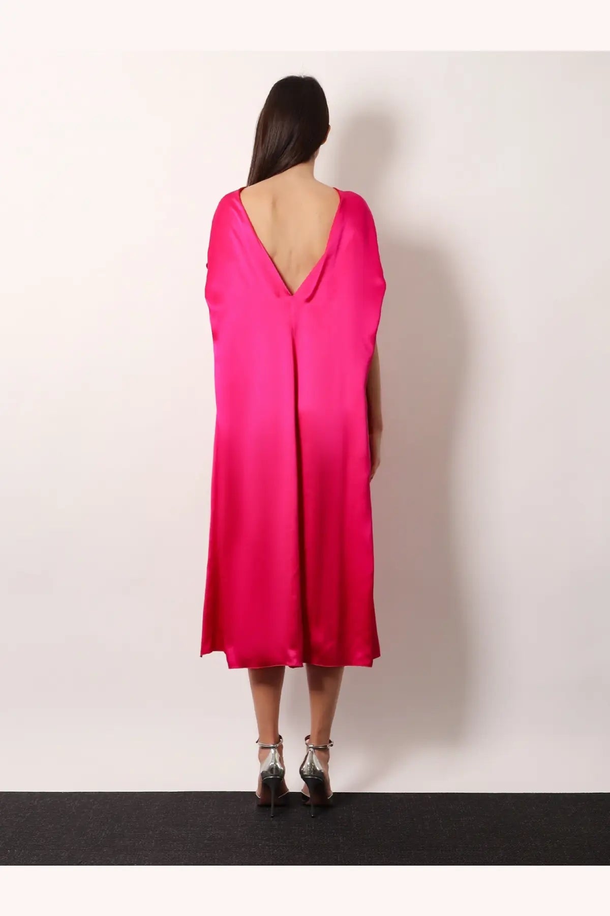 Back view of dries van noten women’s diria silk dress pink vibrant fuchsia satin cape with deep v-back and draped sleeves