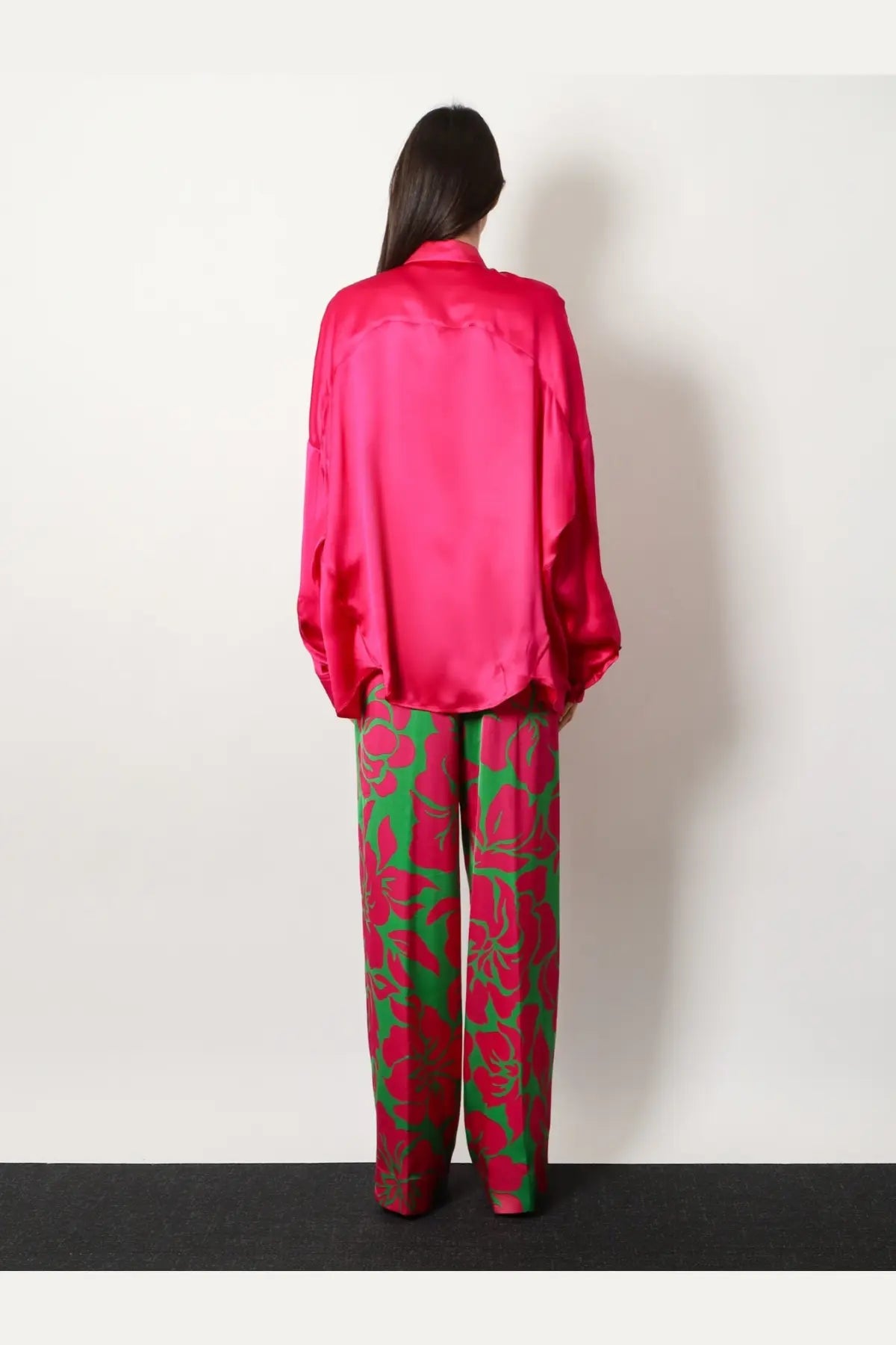 A vibrant fuchsia satin blouse with relaxed fit and long sleeves paired with Dries Van Noten green viscose trousers