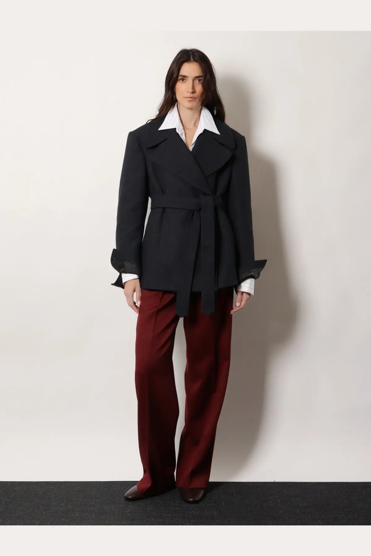Black belted coat with flared sleeves and structured collar paired with dries van noten women’s portias red wool trousers
