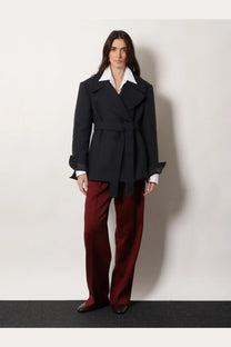 Black belted coat with flared sleeves and structured collar paired with dries van noten women’s portias red wool trousers