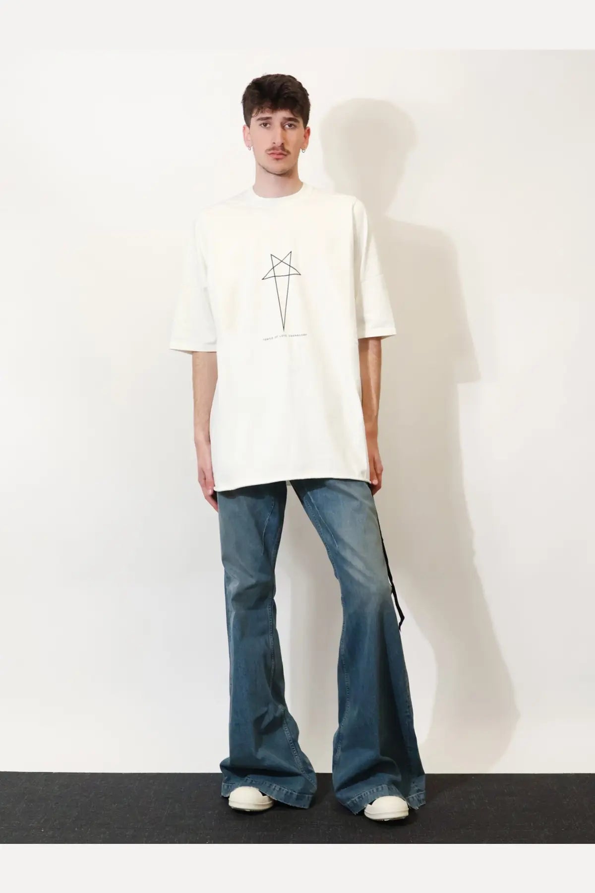 White oversized t-shirt with minimalist black geometric graphic paired with drkshdw men’s blue denim jeans