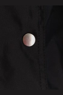 Silver-toned metal button on black recycled nylon fabric of drkshdw men’s convertible jumbo peter flight jacket