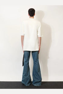 A person wearing a drkshdw men’s black cotton shirt paired with loose off-white t-shirt and dark blue flared jeans