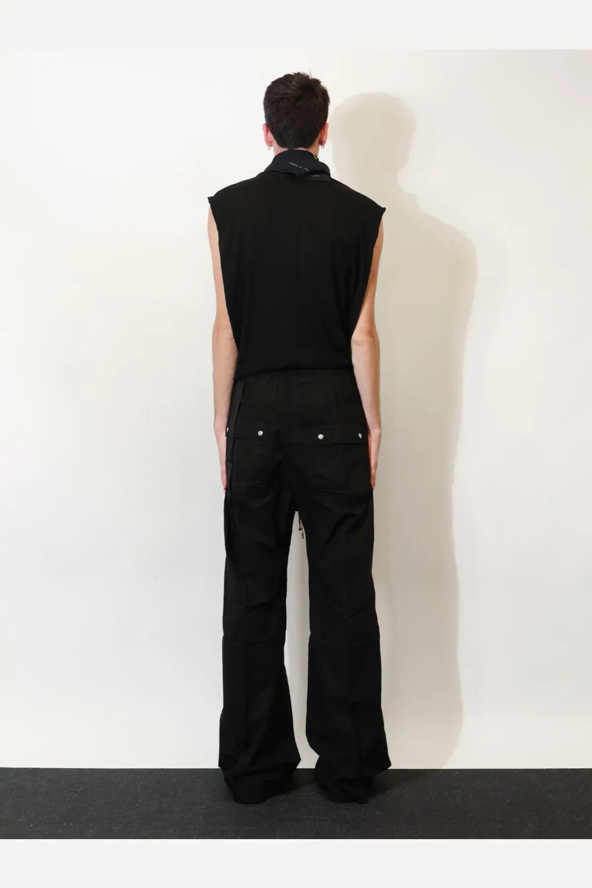 Black sleeveless top with high collar and subtle stitching paired with drkshdw men’s black cotton trousers