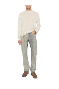 A man wearing drkshdw men’s fog cut jeans blue with light-wash denim and a cream-colored long-sleeved sweater