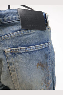 Blue denim drkshdw men’s jeans with vintage wash and black leather brand patch at the waistband back side view