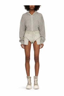 A gray cropped hoodie with front zipper and patch pockets worn over drkshdw women’s dirt beige distressed shorts