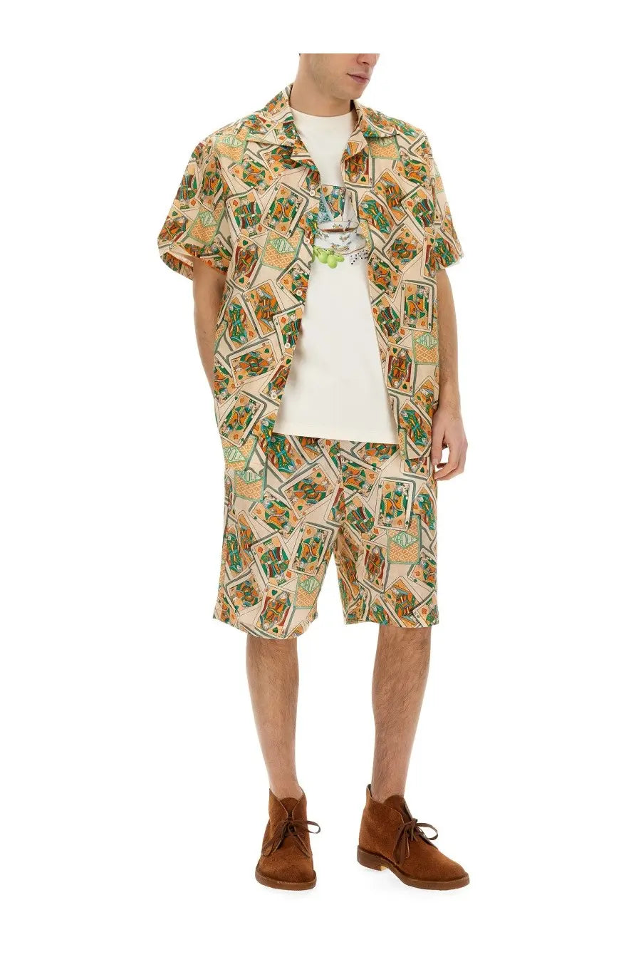 A man wearing a beige short-sleeved cardigan shirt with green and orange playing card print over a white t-shirt