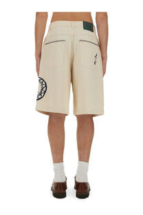 Beige cotton denim shorts by drôle de monsieur with black geometric embroidery and logo patch at waistband