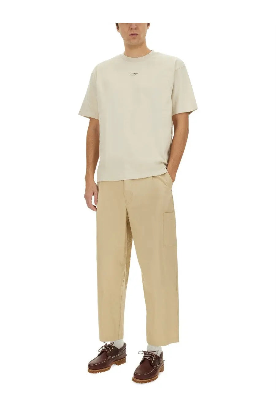 Drôle de Monsieur men’s beige cropped pants paired with a beige short-sleeved cotton t-shirt with minimalist logo