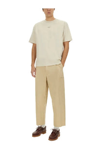 Drôle de Monsieur men’s beige cropped pants paired with a beige short-sleeved cotton t-shirt with minimalist logo