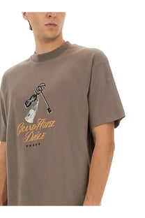 Drôle de monsieur men’s muted gray crewneck t-shirt with black and gold grand hotel drole key and broom graphic