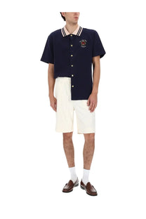 Navy blue short-sleeved polo shirt with white and cream striped collar gold buttons and an embroidered crest on chest