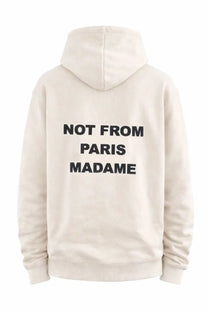 Back view of drôle de monsieur men’s beige cream hoodie with bold black not from paris madame slogan across the back