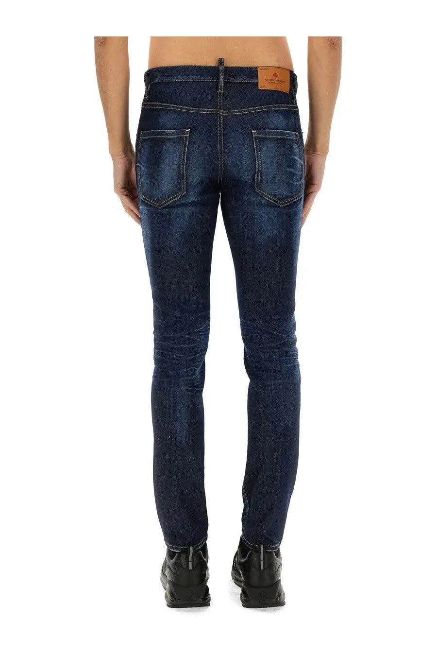 Dark blue slim fit denim jeans with subtle fading and brown leather brand patch at waistband by Dsquared2 men
