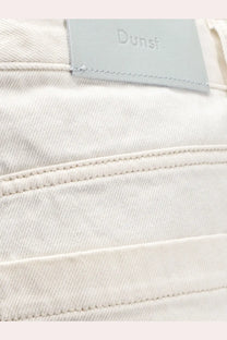 A pair of off-white denim jeans with a textured weave and light gray leather dunst brand patch on the back
