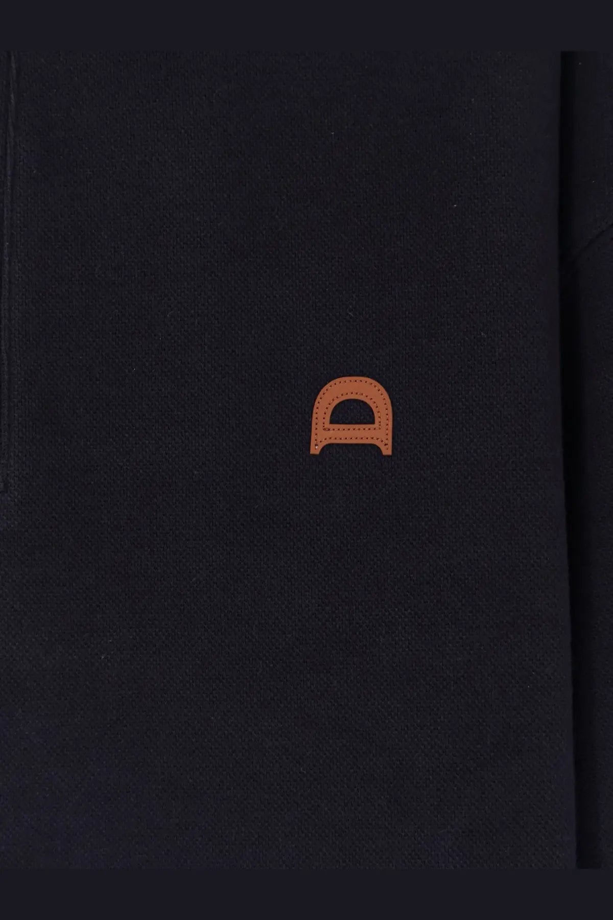 Black textured notebook with subtle orange stitched logo shown with dunst men’s blue cotton polo shirt