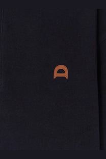 Black textured notebook with subtle orange stitched logo shown with dunst men’s blue cotton polo shirt
