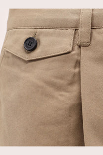 Black button with four holes on beige fabric of dunst men’s pleated brown chino slacks trousers